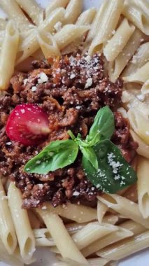 Beyaz tabakta bolonez soslu makarna ve fesleğen.