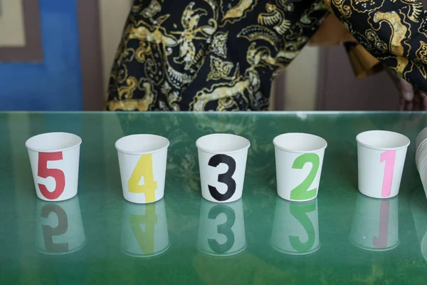 A game of numbers on glasses for early childhood using used glass media. There are numbers 1-5 with different color variants