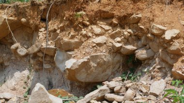 Açık toprak ve taşlarla kaplı kayalık bir arazi doğal erozyon ve jeolojik oluşumlar sergiliyor. Topraksı tonlar ve dokular, doğanın ham elementlerinin güzelliğini ön plana çıkaran engebeli bir manzara yaratır.
