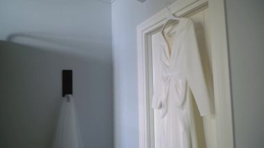 Odadaki askıda asılı beyaz bir gelinlik. Gelinin sabahı. Lüks kadın elbiseleri yatak odasında. Aşk ve evlilik.