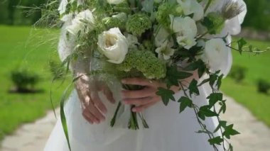 Elbise giymiş bir kadın elinde buket beyaz gül çiçekleriyle. Bir kadın için hediye, tatil, gelinin düğün buketi. Çiçekçilik. İçeride. Düğün günü peçeli gelin.