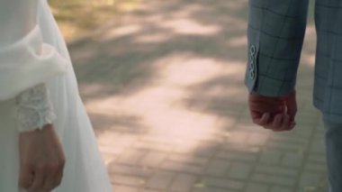 Gelin ve damat el ele tutuşuyor. Beyaz gelinlikli genç bir kadın ve takım elbiseli bir adam. Sevgi, ilgi ve şefkat. Birlikte.