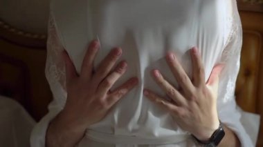 Birbirine aşık bir çift yatakta sarılıyor. Erkek kadına dokunur. Beyaz bornozlu bir kadın ve erkek. Yatak odasında bir sabah, romantik bir randevu. Gelin ve damat, tatildeki ya da balayındaki aşıklar.