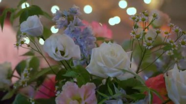 Partide insanlar dans ediyor. Bulanık dans pisti, ön planda çiçekler. Tatil - bir düğün, doğum günü, yıldönümü, ya da başka bir olay. Sahne ışığı.