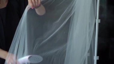 Biri buharlı bir gemi kullanıyor, beyaz bir bez üzerinde buhar püskürtüyor. Elektrikli buhar jeneratörlü demir kıyafetler. Gelinin sabahı, kuru temizleme, duvak ya da gelinlik..