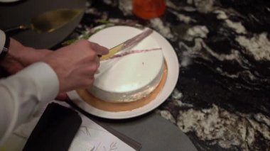 Kutlama pastası kesen biri. Gelin ve damat düğün resepsiyonunda. Bıçak tutan adam ve kadın bir dilim tatlı kestiler..