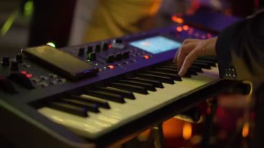 Canlı müzik performansı sırasında, yetenekli ellerle sahnede elektronik sesleri ve büyüleyici melodileri çalan bir synthesizer klavyenin yer aldığı sofistike bir müzik prodüksiyonu kullanılır.