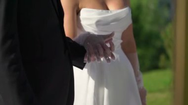 Gelin ve damat el ele tutuşuyor. Beyaz gelinlikli genç bir kadın ve takım elbiseli bir adam. Sevgi, ilgi ve şefkat. Birlikte.