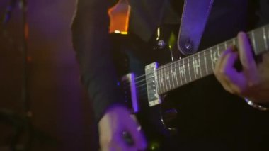 Gitarist gitar çalar. Sahnedeki bir müzik grubunda müzisyen konser veriyor. Sahne ışığı
