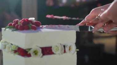 Yeni evlilerin, gelin ve damadın düğünleri sırasında romantik bir pasta yapma deneyimini paylaştıkları güzel bir an. Çiçek ve böğürtlenli beyaz pasta aşkı ve birliği simgeler.