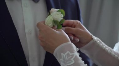 Damat yaka çiçeği takar. Bir kız, bir gelin ya da bir nedime, bir erkek elbisesinde çiçek deliğini düzeltir. Beyaz gömlekli, siyah kravatlı ve yelekli bir erkek..