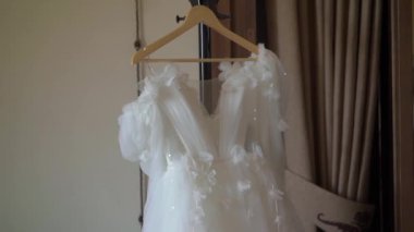Odadaki askıda asılı beyaz bir gelinlik. Gelinin sabahı. Lüks kadın elbiseleri yatak odasında. Aşk ve evlilik.