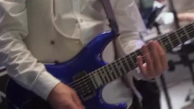 Gitarist bir konserde sahnede gitar çalıyor. Bir adam elektro gitarı tutuyor, panodaki akorları tutuyor. Bir müzik aletinin yakın çekimi. Grubuyla aktif oyuncu rock çalıyor. 