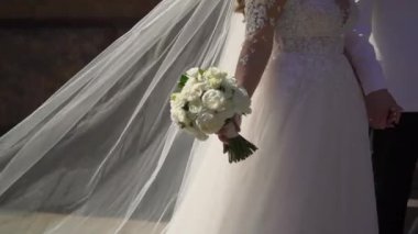 Gelin ve damat kaldırımda yürürler. Erkek ve kadın bacakları, düğün çifti. Beyaz uzun elbiseli kız..