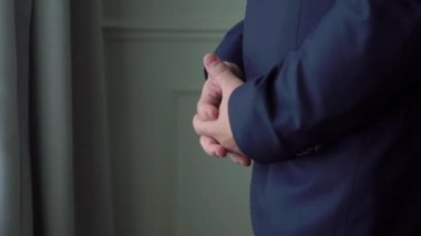 Mavi takım elbiseli bir adam heyecanla bekliyor. Damat, gelini gergin bir şekilde bekliyor, avuçlarını ovuyor..