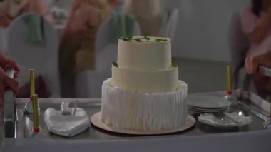 Kutlama pastası kesen biri. Gelin ve damat düğün resepsiyonunda. Bıçak tutan adam ve kadın bir dilim tatlı kestiler..