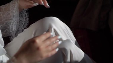 Young girl in a white robe sits on chair with hands. Unrecognizable woman. The bride on the wedding morning. Romance.