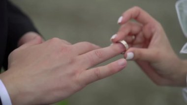 Gelin ve damat düğün töreninde. Adam bir kadın parmağına yüzük taktı. Takı yüzükleri, aşkın sembolü. Yazın açık havada..