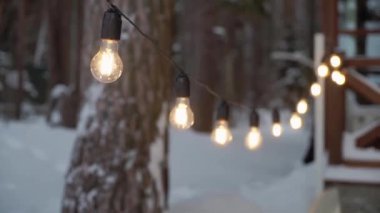 Karlı bir ormanda sarkan sıcak, parıldayan ip ışıkları sıcak bir kış ortamı yaratır. Tatil dekorasyonu ya da açık hava kış manzaraları için ideal ışıklar sizi şenlikli bir atmosfere sokar.