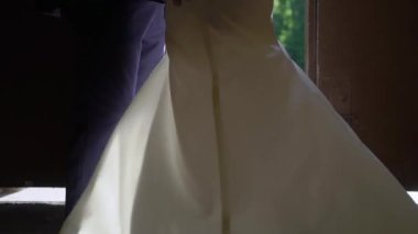 Gelin ve damat sarılıyor. Beyaz gelinlikli, duvağı ve klasik takım elbisesi olan genç bir çift. Karı koca - ilişki, aile, evlilik yıldönümü veya balayı.