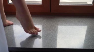 Pencere eşiğinde bir insan ayağı. Genç kadın çıplak ayakla odada daireler çiziyor ve dans ediyor. Beyaz pantolonlu bir kadın. Tanınmayan kızın bacakları..