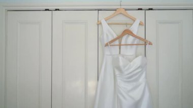 Odadaki askıda asılı beyaz bir gelinlik. Gelinin sabahı. Lüks kadın elbiseleri yatak odasında. Aşk ve evlilik.