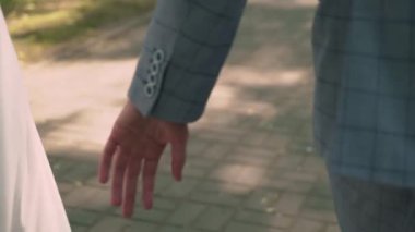 Gelin ve damat el ele tutuşuyor. Beyaz gelinlikli genç bir kadın ve takım elbiseli bir adam. Sevgi, ilgi ve şefkat. Birlikte.