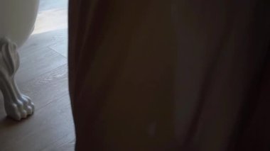 Ahşap zeminde insan ayağı. Genç kadın çıplak ayakla odada daireler çiziyor ve dans ediyor. Beyaz pantolonlu bir kadın. Tanınmayan kızın bacakları..