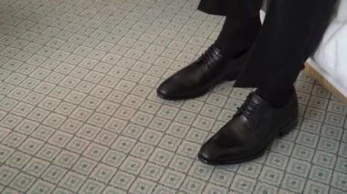 Zeminde bir çift siyah ayakkabı. Tanınmayan adam botlarını giydi ve bağcıklarını bağladı. Tahta ayakkabı çekeceği.. 