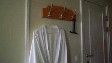 Askıda asılı beyaz ipek kadın bornozu. Siyah erkek papyon..