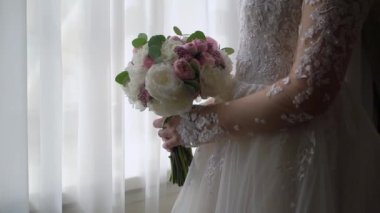 Elbise giymiş bir kadın elinde buket beyaz gül çiçekleriyle. Bir kadın için hediye, tatil, gelinin düğün buketi. Çiçekçilik. İçeride. Düğün günü peçeli gelin.