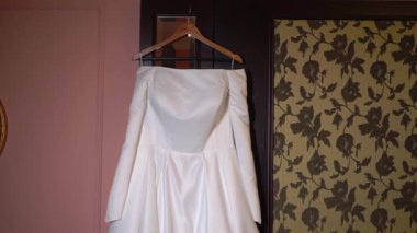 Odadaki askıda asılı beyaz bir gelinlik. Gelinin sabahı. Lüks kadın elbiseleri yatak odasında. Aşk ve evlilik.