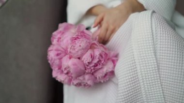 Elbise giymiş bir kadın elinde buket beyaz gül çiçekleriyle. Bir kadın için hediye, tatil, gelinin düğün buketi. Çiçekçilik. İçeride. Düğün günü peçeli gelin.