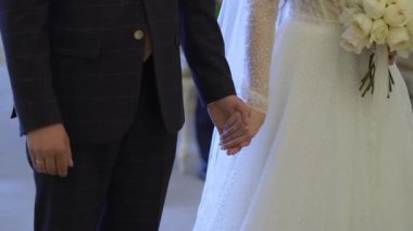 Gelin ve damat el ele tutuşuyor. Beyaz gelinlikli genç bir kadın ve takım elbiseli bir adam. Sevgi, ilgi ve şefkat. Birlikte.