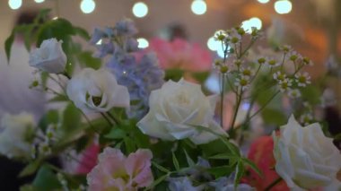 Partide insanlar dans ediyor. Bulanık dans pisti, ön planda çiçekler. Tatil - bir düğün, doğum günü, yıldönümü, ya da başka bir olay. Sahne ışığı.