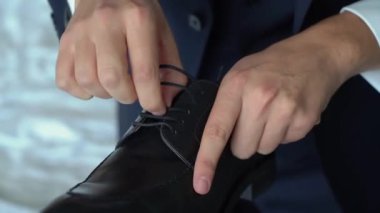 Zeminde bir çift siyah ayakkabı. Tanınmayan adam botlarını giydi ve bağcıklarını bağladı. Tahta ayakkabı çekeceği.. 