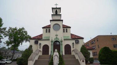 Karmaşık bir mimari ve güzel bir heykel ile çarpıcı bir kilise cephesi bulutlu bir gökyüzüne karşı duruyor, insanları ibadet, yansıma, dinginlik ve maneviyat anlarına davet ediyor.