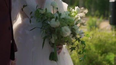 Elbise giymiş bir kadın elinde buket beyaz gül çiçekleriyle. Bir kadın için hediye, tatil, gelinin düğün buketi. Çiçekçilik. İçeride. Düğün günü peçeli gelin.