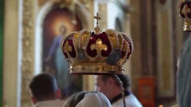 Düğünde kilisede taçlar. Ortodoks Hıristiyan ya da Katolik katedrali. Evlilik için haçlı altın şapkalar. Rahip bir ayin düzenler, duaları okur..