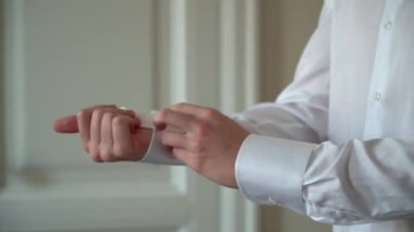 Adam beyaz gömlek giyip düğmelerini ilikliyor. Damadın düğün gününün sabahında, kişi parti, tatil ya da etkinlik için giyinir. İş adamı takım elbise giyer..