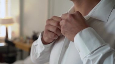 Adam beyaz gömlek giyip düğmelerini ilikliyor. Damadın düğün gününün sabahında, kişi parti, tatil ya da etkinlik için giyinir. İş adamı takım elbise giyer..