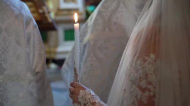 Düğün töreninde gelin ve damat ellerinde mumlarla kilisede. Hıristiyanlık ya da Katoliklik, Tanrı 'ya inanç. Kilise ayini. Rahip ödüyor..