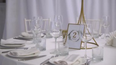 Gözlüklü ve tabaklı bir düğün resepsiyonu için masa ayarlama. Kapalı resepsiyon salonu.