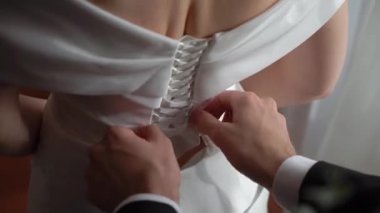 Bir elbiseye korse bağlayan biri. Gelinliğini giy. Gelin ve damadı. Beyaz bir elbise giyen genç bir kadın..