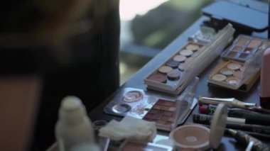 Görüntü, makyaj araçlarının, paletlerin ve fırçaların detaylı bir görüntüsünü yakalayarak, bir makyaj sanatçısının çalışma alanındaki düzenini gözler önüne seriyor.