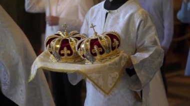 Düğünde kilisede taçlar. Ortodoks Hıristiyan ya da Katolik katedrali. Evlilik için haçlı altın şapkalar. Rahip bir ayin düzenler, duaları okur..