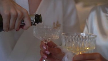 Adam şampanyadan bardaklara şampanya dolduruyor. Beyaz köpüklü alkollü şarap içeceği. Romantik randevu tatilindeki çift, erkek ve genç kadın..