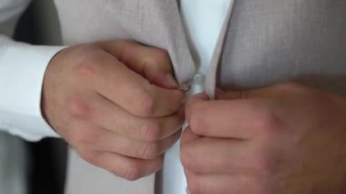 Bir adam cekete ya da yeleğe düğme takıyor. Erkek klasik bir takım elbise giyer. İş adamı, ofis çalışanı ya da damat..