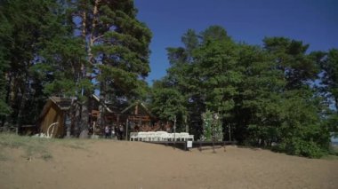 Çiçek ve sandalyeli düğün kemeri. Seremoni salonu açık havada. Beyaz çiçekler ve yeşilliklerle süslenmiş. Güneşli yaz günü.