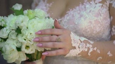 Elbise giymiş bir kadın elinde buket beyaz gül çiçekleriyle. Bir kadın için hediye, tatil, gelinin düğün buketi. Çiçekçilik. İçeride. Düğün günü peçeli gelin.